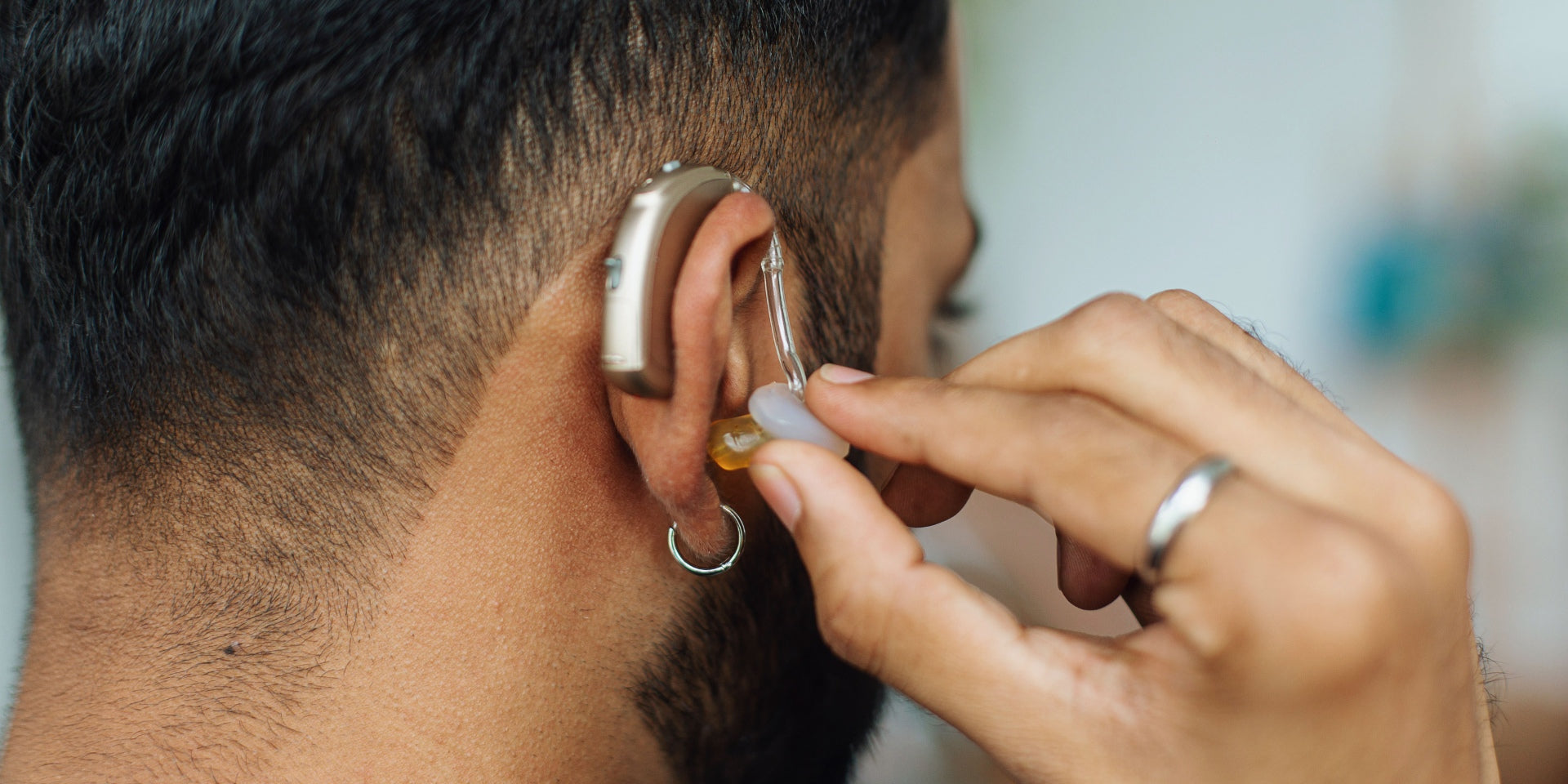 Man confidently inserting a hearing aid.
